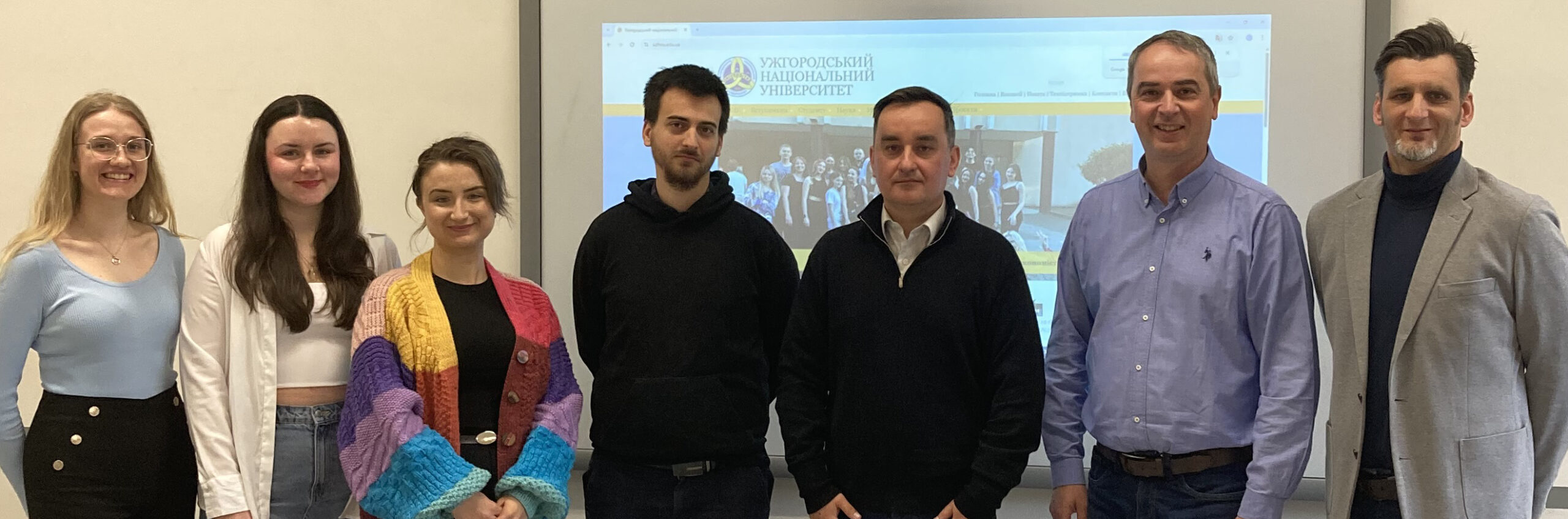 Group photo from a EURIDICE project event at Pavol Jozef Šafárik University in Košice, featuring faculty and students alongside Assoc. Prof. Igor O. Shnitser of Uzhhorod National University. The image on the projector screen is partially visible and relates to digital education challenges in Ukraine.